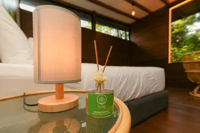 a lamp on a table next to a bed at The HIJAU Camp & Cabin in Gopeng