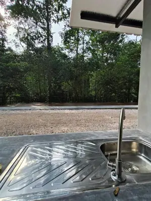 a stainless steel sink with a view of a field at The HIJAU Camp & Cabin in Gopeng