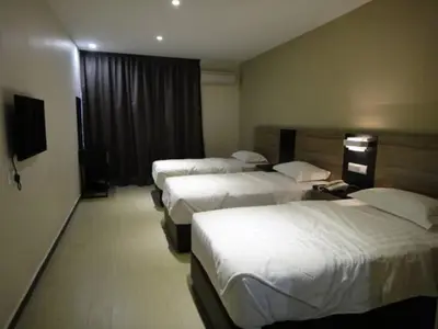 a hotel room with four beds in a row at Galaxy Hotel SIMPANG AMPAT in Simpang Ampat