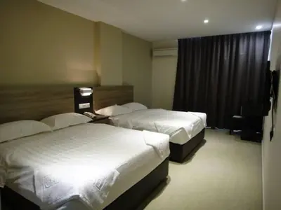 a hotel room with two beds and a window at Galaxy Hotel SIMPANG AMPAT in Simpang Ampat