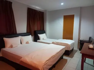 a hotel room with two beds and a desk at Reintree Lodge Hotel Ipoh in Ipoh