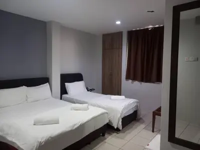 a hotel room with two beds and a mirror at Reintree Lodge Hotel Ipoh in Ipoh
