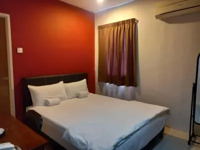 a bedroom with a white bed with a red wall at Reintree Lodge Hotel Ipoh in Ipoh