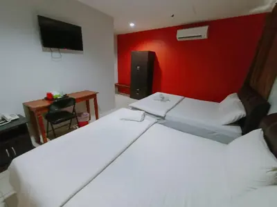 a hotel room with two beds and a red wall at Reintree Lodge Hotel Ipoh in Ipoh