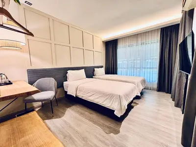 a hotel room with two beds and a table and a desk at Regent Event & Leisure in Ipoh