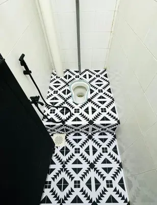 a bathroom with a white and black tile floor with a toilet at Warisan Guest House Ipoh in Ipoh
