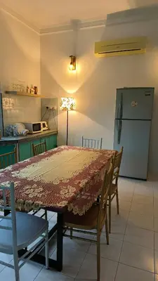 a kitchen with a table with chairs and a refrigerator at Frangipine Villa in Tapah