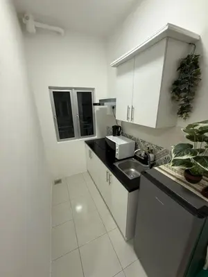 a white kitchen with a sink and a counter top at Kyra's Downtown Delight in Ipoh