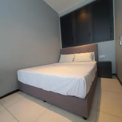 a bedroom with a bed with white sheets and cabinets at Urban Suites - Family Suite in Jelutong