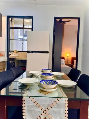 a kitchen with a table with plates and a refrigerator at Relax & Unwind 2BR Apartment with 5 Queen Beds in Jelutong