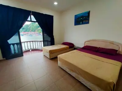 a bedroom with two beds and a window with a view at Capital O 91118 Chalet Seri Idaman in Kampong Batu Maung
