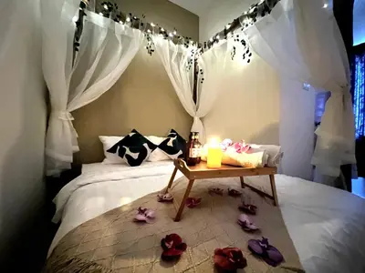 a bedroom with a bed with a candle and flowers on the floor at The Little Bali Romance 2pax#Private Bathroom#2min KekLokSi in Ayer Itam