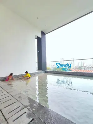two children playing in a swimming pool in a building at Bright & airy 3BR homestay comfort penang Netflix in George Town