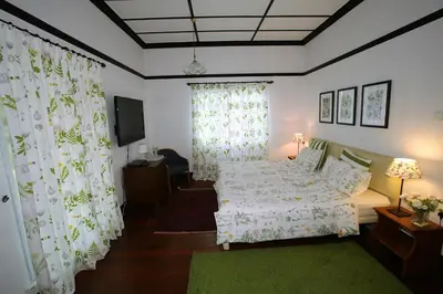 a bedroom with a bed and curtains and a television at Bukit Lowick Bungalow in Tanah Rata