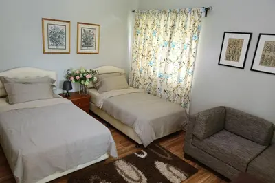 a bedroom with two beds and a chair and a window at Bukit Lowick Bungalow in Tanah Rata