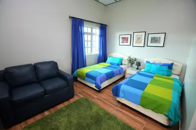 a bedroom with two beds and a couch at Bukit Lowick Bungalow in Tanah Rata