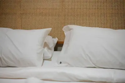 a bed with two white pillows and a wall at DeLuma - Lebuh Melayu 4 Bedroom in George Town