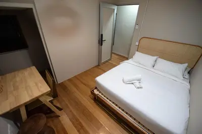 a small bedroom with a bed with white sheets and a table at DeLuma - Lebuh Melayu 4 Bedroom in George Town