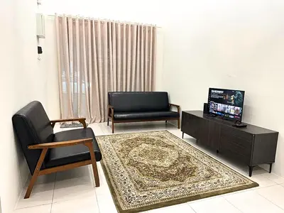a living room with a couch and a chair and a television at Homestay Bunga Raya Wifi Netflix in Sitiawan