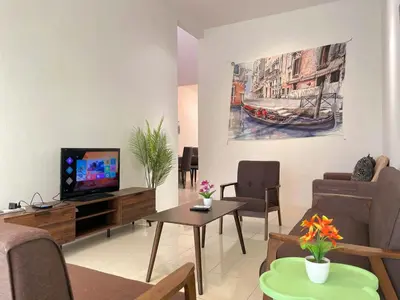 a living room with a tv and a couch and a table at Jovial Single Storey Cozy Haus 9Pax in Lunas