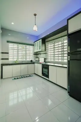 a large kitchen with white cabinets and appliances at Dyra Homestay in Lumut in Lumut