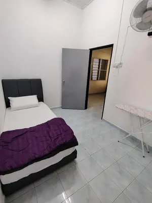 a bedroom with a bed with a purple comforter at Suria Permai19 Homestay in Taiping