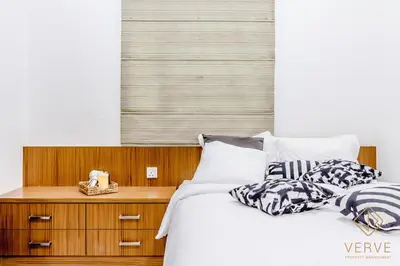 a bed with two pillows and a wooden night stand at Ipoh Lang Villa Premium Semi-D Villa by Verve in Ipoh