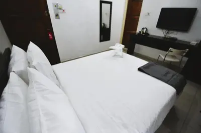 a large white bed in a room with a television at AZYA Hotel in TanjongMalim