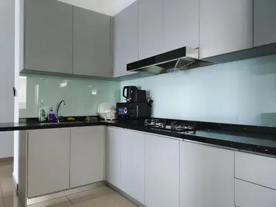 a kitchen with white cabinets and black counter tops at Metropol Serviced Apartment - Bukit Mertajam, Penang in Bukit Mertajam