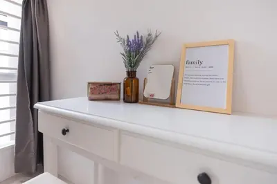 a white dresser with a picture and flowers on it at Taiping Bali Home 5R3B, 7mins-Tpg Lake Gardens in Taiping