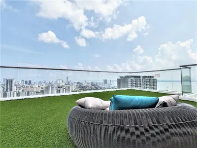 a wicker couch sitting on a balcony with a view of a city at Urban Suites, 2 Rooms, 5 Pax, Free Car Park in Jelutong