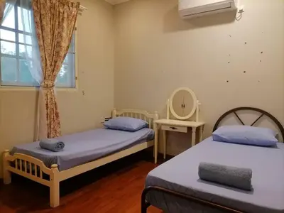 two beds in a room with a window and a mirror at Anandavilla in Seri Manjung