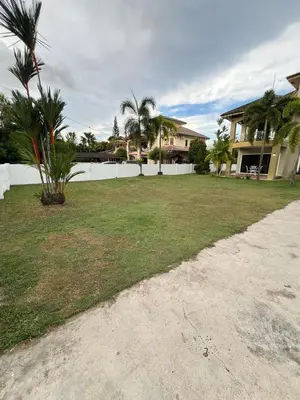 a yard with palm trees and a white fence at Anandavilla in Seri Manjung