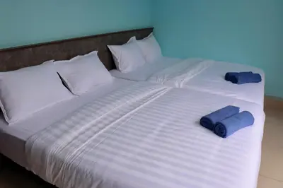 a large white bed with two blue pillows on it at Hotel Aaraa in Brinchang