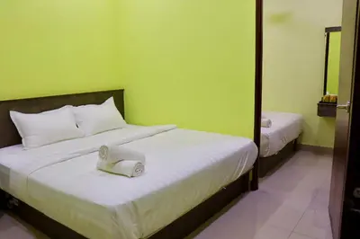 a bedroom with two beds and a green wall at Hotel Aaraa in Brinchang
