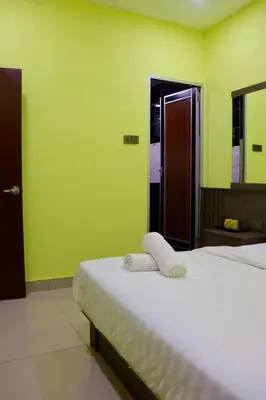 a bedroom with a white bed with green walls at Hotel Aaraa in Brinchang