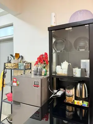 a kitchen with a shelf with dishes and a refrigerator at Shahiqa Homestay Cameron Highland in Brinchang