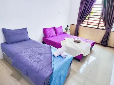 two beds and a table in a room with purple sheets at 30 Bercham Double-Storey Homestay in Ipoh