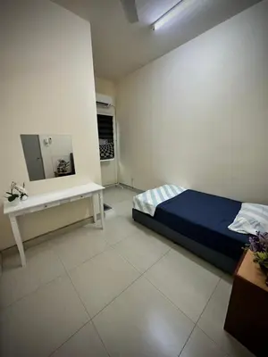 a bedroom with a bed and a table and a mirror at Homestay Adyana in Raub