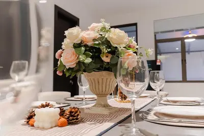 a table with a vase filled with flowers and glasses at Georgetown Italian-Style Jacuzzi KTV 5BR 18pax G in George Town