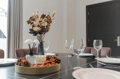 a table with a centerpiece of flowers and wine glasses at Georgetown Modern Brown-Colored KTV 5BR 18pax H in George Town