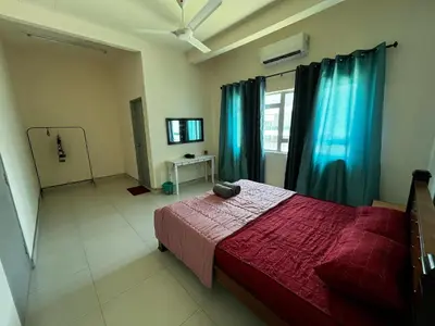 a bedroom with a bed and a window with blue curtains at Homestay Adyana in Raub