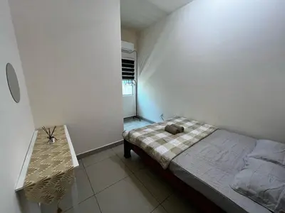a small bedroom with a bed and a table at Homestay Adyana in Raub