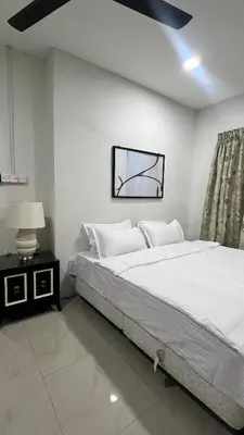 a white bedroom with a large bed and a lamp at Villa Alyana in Ipoh