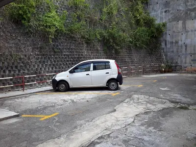 a small white car parked in a parking lot at Rasa Motel in Batu Ferringhi
