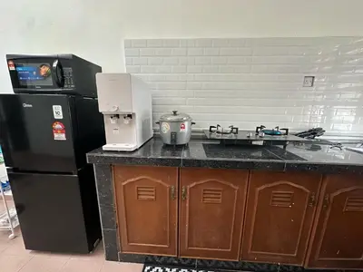 a kitchen with a black refrigerator and a counter with a coffee maker at Rafeeqs Homestay in Teluk Intan