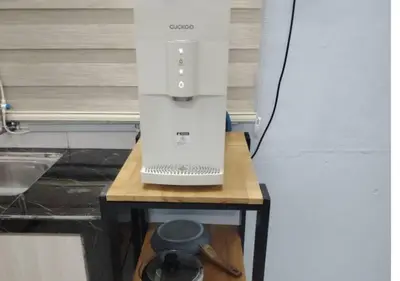 a white appliance sitting on top of a wooden table at Homestay Zainab Sg Dua Mslim With 100mbps Wifi in Kepala Batas