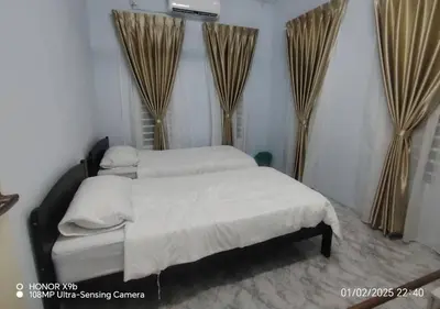 a bedroom with two beds with curtains in it at Homestay Zainab Sg Dua Mslim With 100mbps Wifi in Kepala Batas