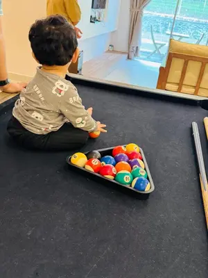 a young child sitting on the floor with a tray of balls at AYAAN SNOOKERS HOUSE at QUINTET FREE PARKING and NETFLIX in Tanah Rata