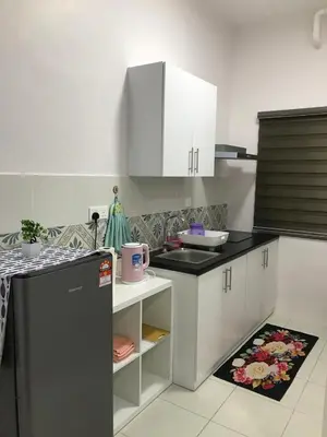 a kitchen with white cabinets and a black counter top at VS Homestay in Ipoh